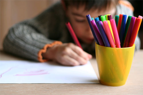 young boy colouring a drawing in